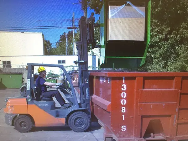 Gaylord hopper being tipped over with a forklift. The hopper is dumping material into a bigger bin