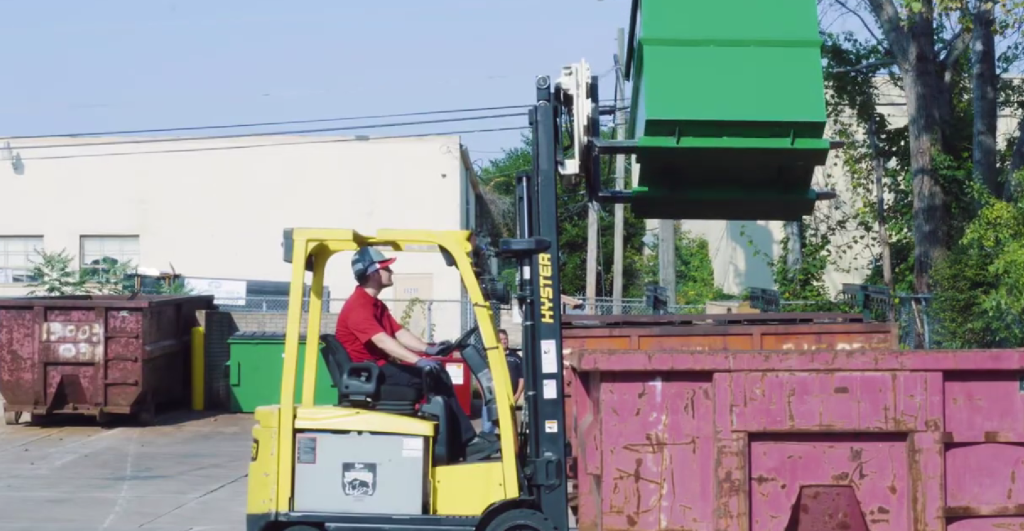 A forklift operator slowly rotates a rotator box