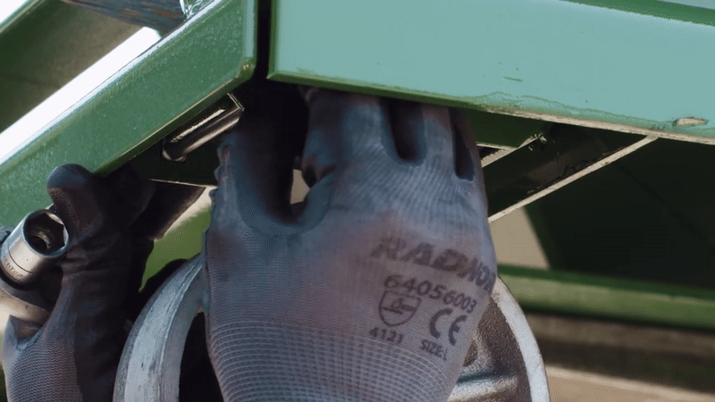 A person tightens the nut on the bolt with a ratchet wrench