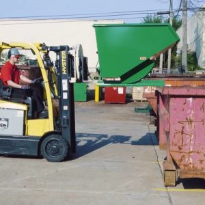 A hopper being used with a forklift. The hopper is about to be emptied into a dumpster